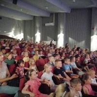 Dzieci siedzą na sali kinowej i ogladają spektakl pod tytułem 