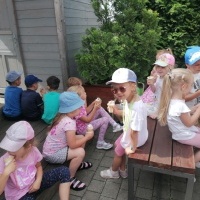 Dzieci siedzą przy stoliku. Jedzą lody. 