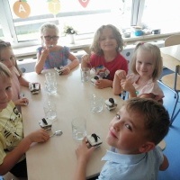 Dzieci siedzą przy stoliku i zjadają deser.