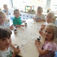 Dzieci siedzą przy stoliku i zjadają deser.