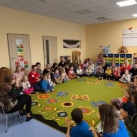 Dzieci i rodzice wykonują jesienny masażyk. W tle zabawki. 