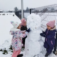 Trzy dziewczynki lepią bałwana.