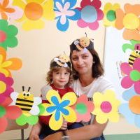 Nauczycielka z chłopcem w ramce z kolorowych kwiatów. Na głowach mają opaski z pszczółkami.