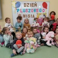 Grupa dzieci siedzi przed tablicą magnetyczną z napisem 