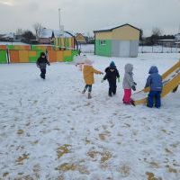 Dzieci biegają, rzucają się śnieżkami na placu zabaw. 