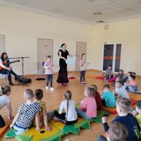 Dzieci siedzą na materacach i obserwują pokaz Instruktora Flamenco i koleżanek .