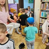 Pani z biblioteki oprowadza dzieci po bibliotece, pokazując książki.