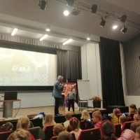 Wojciech Widłak oraz dziecko na scenie w tle ilustracje do książek.