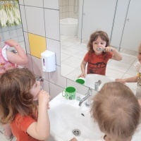 Dwójka dzieci myje zęby przed lustrem w przedszkolnej łazience. 
