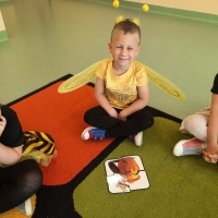 Chłopczyk w stroju pszczółki siedzi na dywanie. Przed nimi leży obrazek z puzzli.
