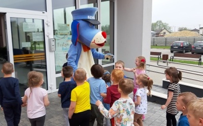 Sznupek stoi  przed drzwiami przedszkola  i wita się z każdym dzieckiem.