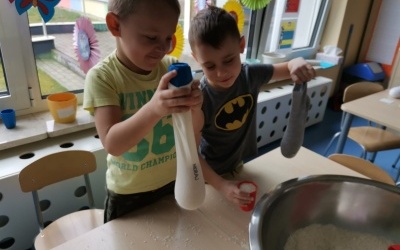 Dwóch chłopców wsypuje ryż do skarpet.