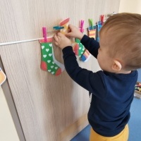 Chłopczyk przyczepia klamerkami skarpetki na sznurek. 