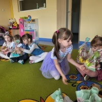 Grupa dziewczyn siedzi na dywanie i trzyma prezenty wielkanocne.