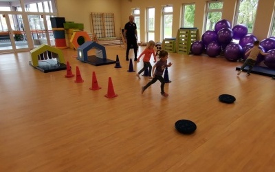 Dzieci biegają wokół  pachołków , rywalizują w zawodach sportowych.