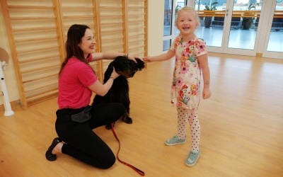 Trenerka Monika i pies Lili razem z dziewczynką która ogląda psie uszy.