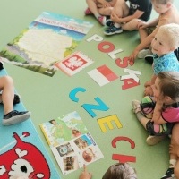 Grupa dzieci poznaje symbole Czech. W tle dywan. 