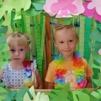 Dziewczynka i chłopiec stoją w hawajskiej ramce. W tle bibuły. 
