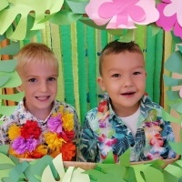 Chłopcy stoją w hawajskiej ramce. W tle bibuły. 
