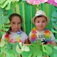Dziewczynka i chłopiec stoją w hawajskiej ramce. W tle bibuły. 