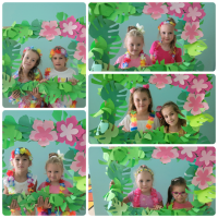Dziewczynki w strojach hawajskich pozują do zdjęcia w zielonej ramce.