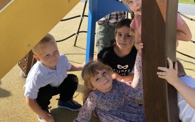 Grupa dzieci na przedszkolnym placu zabaw.