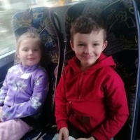 Dwójka dzieci siedzi w autobusie. W tle okno. 