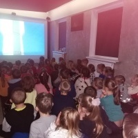 Grupka dzieci patrzy na prezentację o kosmosie. W tle okna.
