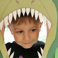 Chłopczyk pozuje do zdjęcia z fotobudką dinozaura.