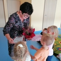 Dzieci wręczają pani kwiatek za przeczytanie bajki. 