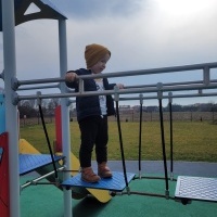 Chłopczyk w żółtej czapce bawi się na placu zabaw.