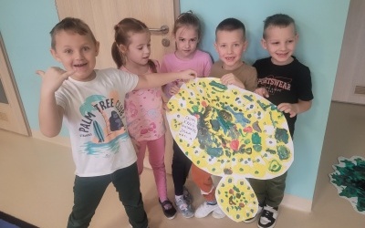 Grupa dzieci prezentuje obrazek wirusa wykonany farbami.
