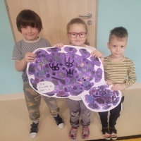 Grupa dzieci prezentuje obrazek wirusa wykonany farbami.