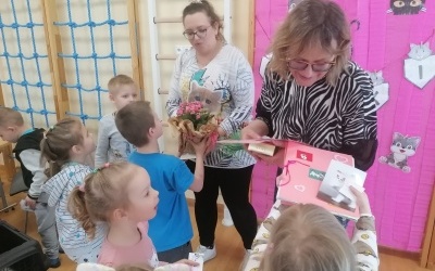 Dzieci wręczają prezenciki paniom, które hodują koty. W tle drabinki. 