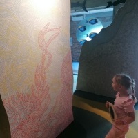 Dziewczynka patrzy na kolorowe rybki. W tle kolorowe ściany. 