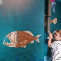 Chłopiec nasłuchuje głosu koleżanki. W tle ryba. 