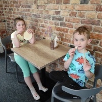 Chłopiec i dziewczynka siedzą przy stoliku i jedzą wafelki.