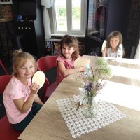 Trzy dziewczynki siedzą przy stoliku i jedzą wafelki. 