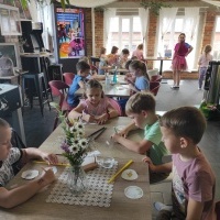 Dzieci siedzą przy stolikach. Tworzą ze słomek rybki. 