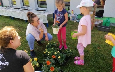 Dwie dziewczynki razem z dwoma paniami florystkami wybierają kwiaty dla mamy.